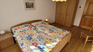 A bedroom with a wooden bed, a nightstand, a lamp, a wooden wardrobe, and a framed picture on the wall. - Metropol B19, (Grächen), 1079 by Interhome (Grächen)