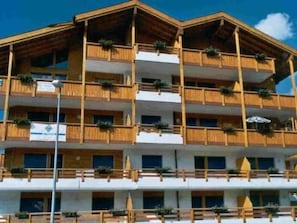 A multi-story building with balconies, each with potted plants. - Metropol B19, (Grächen), 1079 by Interhome (Grächen)