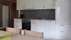 A modern kitchen with white cabinets, a built-in oven, and a coffee maker. - Chalet Heimatglück, (Grächen), 1179 - 1181 by Interhome (Grächen)