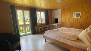 A room with a bed, a chair, a TV, and a balcony with a view. - Chalet Heimatglück, (Grächen), 1179 - 1181 by Interhome (Grächen)