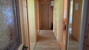 A wooden hallway with a ceiling light, wooden walls, and a door at the end. - Chalet Heimatglück, (Grächen), 1179 - 1181 by Interhome (Grächen)