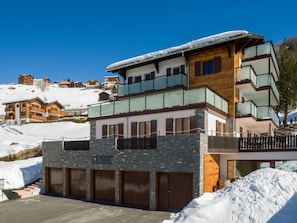 A multi-story hotel with a stone facade, balconies, and a snow-covered roof.