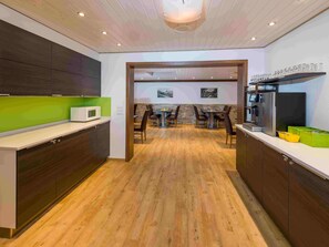 A modern kitchen with wooden flooring, built-in cabinets, a microwave, and a coffee machine. - Ferienwohnungen Lunic, AZapartments.ch, B&B, (Grächen), 1057 by Interhome (Grächen)