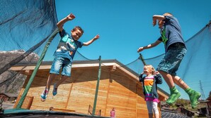 A trampoline with netted sides, wooden flooring, and a clear blue sky in the background. - Lunic, AZapartments.ch, B&B, (Grächen), 1057 by Interhome (Grächen)