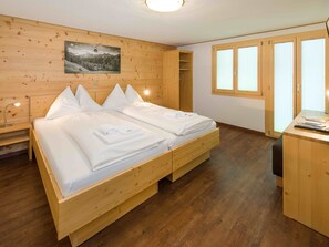 A wooden room with a bed, a desk, and a window.