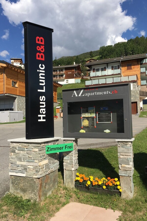 A sign for Haus Lunic B&B with a stone base and a green sign indicating Zimmer Frei.