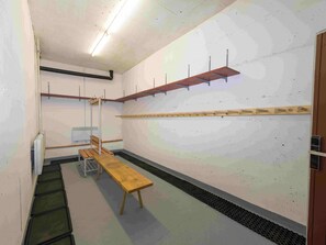 Una habitació amb una banca, un radiador, una prestatgeria amb ganyots i una porta.