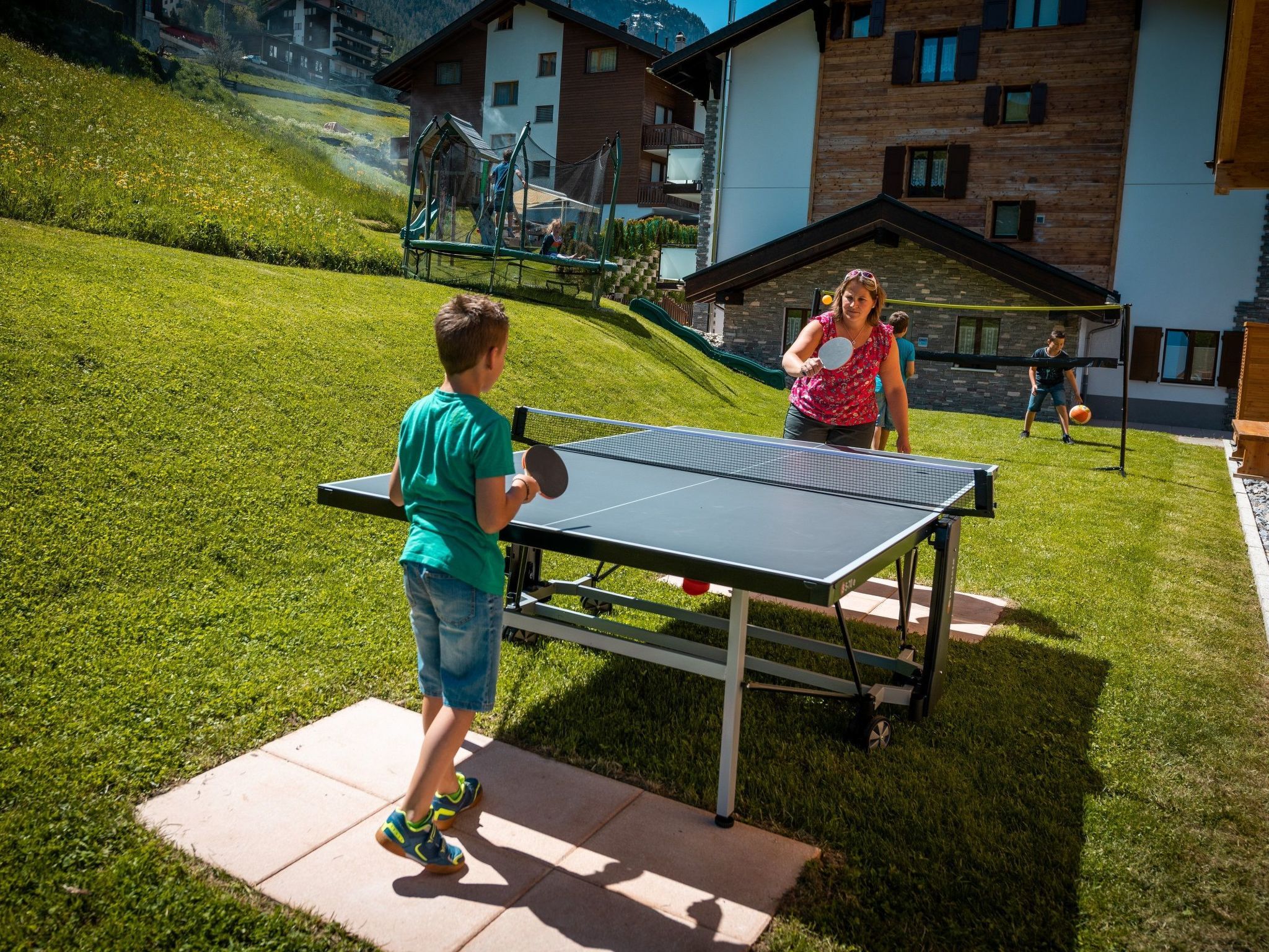 Ett bordtennisbord placerat utomhus på en gräsyta, med en byggnad i bakgrunden.