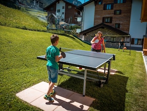 Un tavolo da ping pong all'aperto su un prato, con un edificio sullo sfondo.