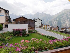 Ein Bergdorf mit Holzhäusern, einer Straße und Blick auf die Berge.