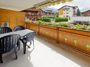 Ein Balkon mit Holzbalkon, Tisch und Stühlen.
