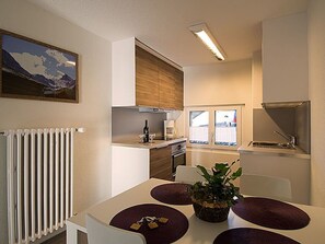 A compact kitchen with a dining area, a radiator, and a window with a view. - Ferienwohnungen Soldanella, (Grächen), by Interhome (Grächen)