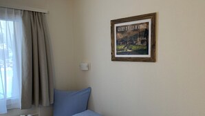 A single bed with a blue blanket, a window with curtains, and a framed picture on the wall. - Soldanella, (Grächen), by Interhome (Grächen)