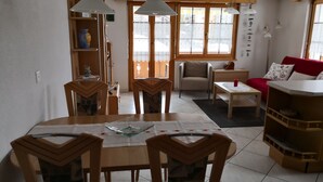 Un comedor con una mesa y sillas de madera, un sofá rojo y una estantería.