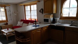 Una cocina compacta con comedor, armarios de madera, microondas y un lavamanos.