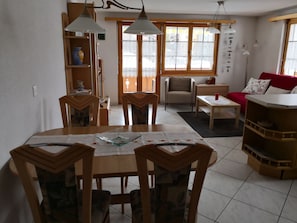 A dining area with a wooden table and chairs, a sofa, and a red couch. - Wohnung Nr. 19 Sierra Vista, (Grächen), 5002 by Interhome (Grächen)