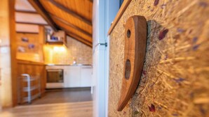 Tunnelmallinen, maalaishenkinen sisustus, jossa on puinen kattopaneeli, keittiöalue ja puinen seinä, jossa on pyöreä aukko.