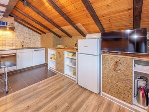 A kitchen with wooden beams, a tiled backsplash, a refrigerator, a stove, and a television. - apartment EFEU "mit stil & tradition", (Grächen), 1461 by Interhome (Grächen)