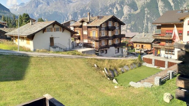 Un village de montagne avec des bâtiments traditionnels en bois, un hôtel et un petit étang.