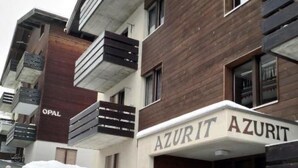 Un bâtiment moderne avec une enseigne indiquant « AZURIT » et une clôture en bois à l’avant.