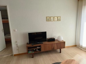 A living room with a TV, a white spherical object, and a wooden cabinet. - Ferienwohnunung Nr.22,Haus Azurit, (Grächen), 1201 by Interhome (Grächen)