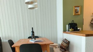 Un espace repas comprenant une table en bois, des chaises, un banc et un luminaire suspendu.