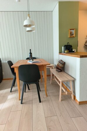 A dining area with a wooden table, chairs, a bench, and a hanging light fixture. - Ferienwohnunung Nr.22,Haus Azurit, (Grächen), 1201 by Interhome (Grächen)