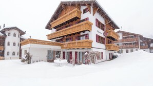 A multi-story hotel with balconies, a snow-covered landscape, and a clear sky. - Ferienwohnungen Miranda, (Grächen), by Interhome (Grächen)