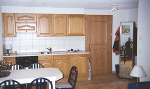 Een koelkast, een oven, kookgerei, borden en bestek