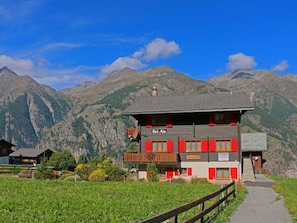 A two-story building with a balcony, surrounded by mountains and a clear sky. - Ferienwohnungen Bel Air, (Grächen), 1292 & 1575 by Interhome (Grächen)