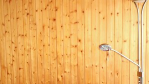 Un canapé à carreaux rouges dans une pièce aux murs lambrés et dotée d’un lampadaire.