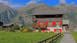 Un bâtiment à deux étages doté d’un balcon, entouré d’un paysage montagneux.