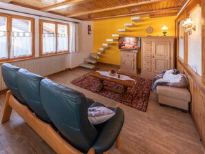 En hyggelig stue med sofa, sofabord, pejs og trappe op til en etage.