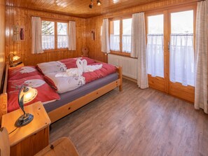 Et hyggeligt træsomrum med seng, skrivebord, lampe og et vindue med gardiner.