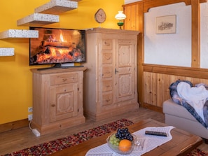 Ein gemütliches Wohnzimmer mit Kamin, Holzschränken, Fernseher und einer Couch.