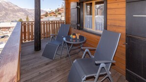 A wooden deck with two chairs and a table, overlooking a mountainous area. - Dominique, (Grächen), 1013 by Interhome (Grächen)