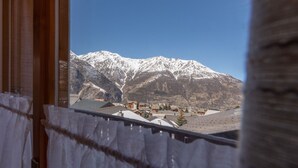 A mountain view through a window with a wooden frame and white curtains. - Dominique, (Grächen), 1013 by Interhome (Grächen)