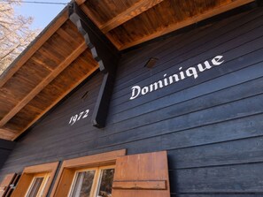 Ein Gebäude mit dunkler Holzfassade und dem Schriftzug 'Dominique'.