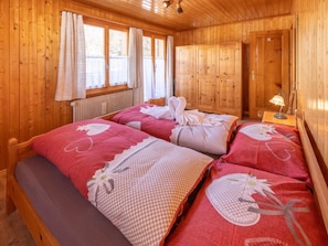 Ein Zimmer mit Holzboden, zwei Betten, einem Heizkörper und einer Tür.