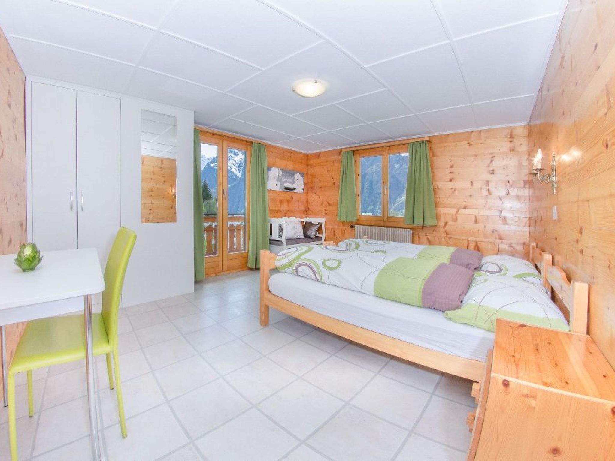 Quarto com cama, escrivaninha e cadeira.