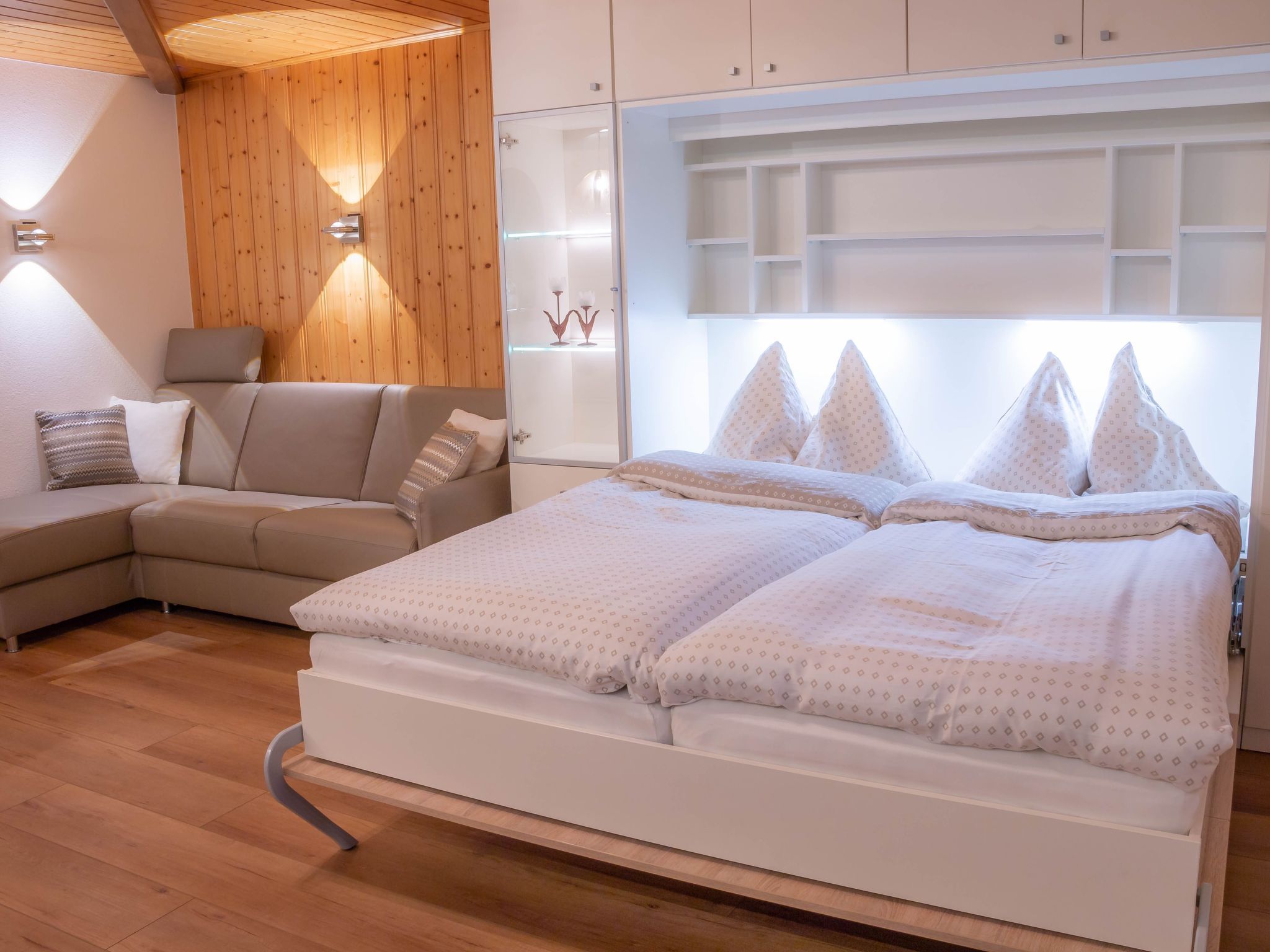 Een slaapkamer met een bed, een bank en een houten wand met een lamp.