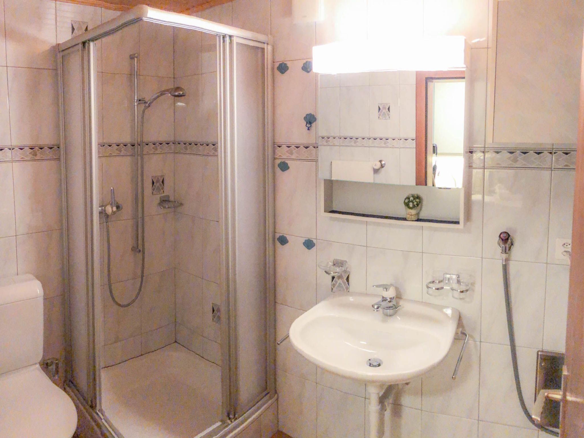 A bathroom with a glass-enclosed shower, a sink, and a mirror above it.
