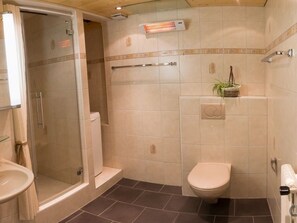 Un baño con ducha, inodoro y barra para toallas.