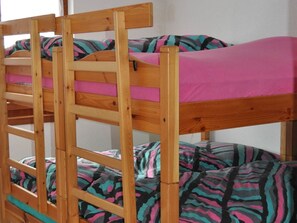Ein Etagenbett mit Holzgestell und bunter Bettwäsche.