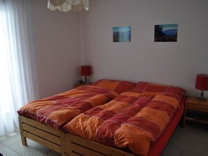 Ein Schlafzimmer mit einem hölzernen Bett, zwei Nachttischen mit Lampen und zwei an der Wand befestigten Bildern.