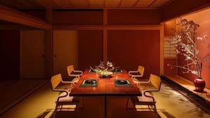 A traditional Japanese-style dining room with a low table, wooden chairs, and a vase of flowers. - Hogetsu (Kagoshima)