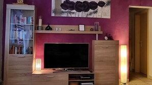 Un salon avec un téléviseur, une bibliothèque et des œuvres d’art accrochées au mur.