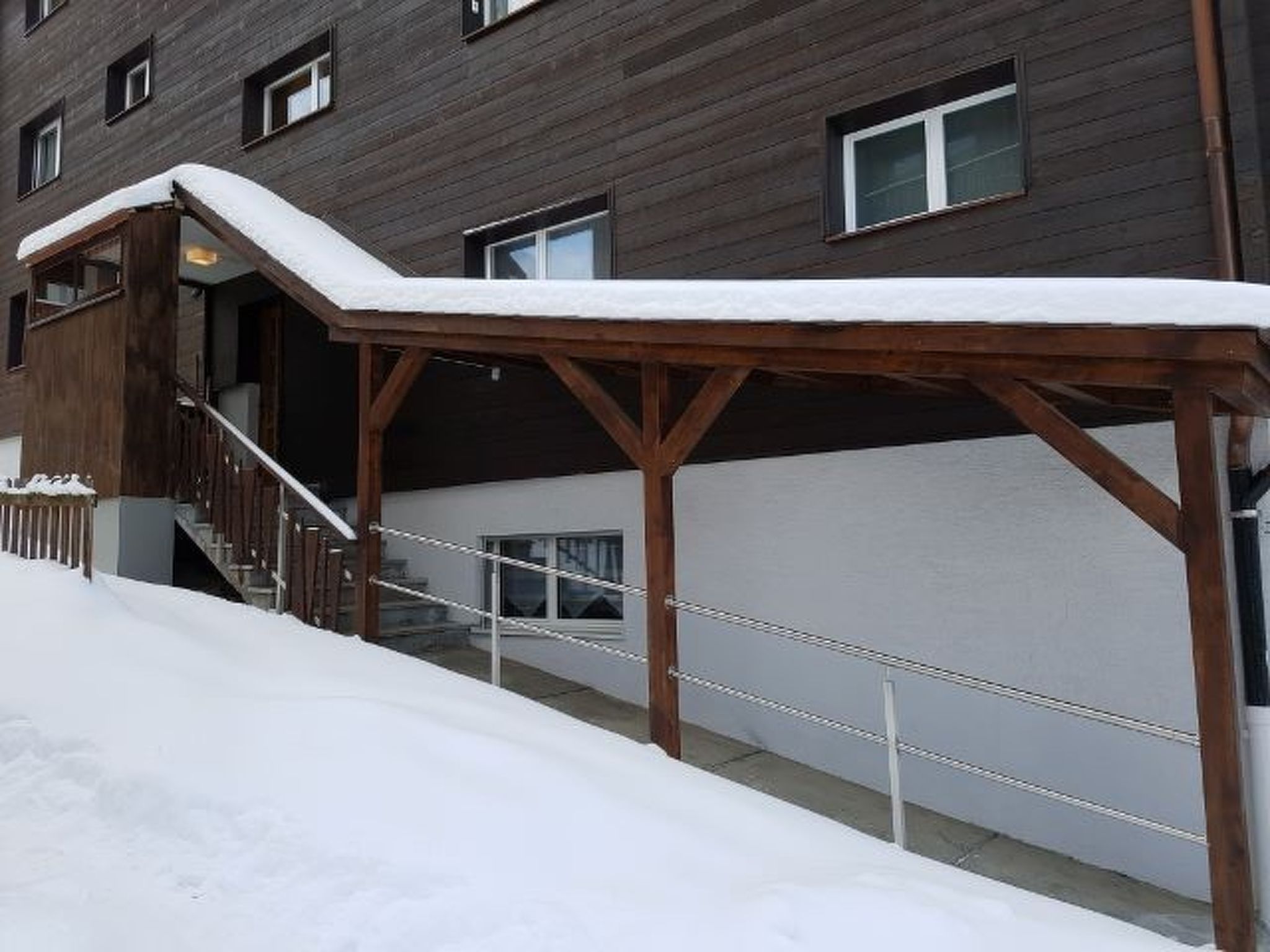 A building with a wooden staircase and a covered outdoor area.