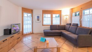 Ein Wohnzimmer mit Ecksofa, Couchtisch, Fernseher und Kamin.