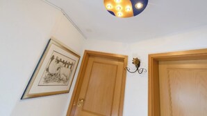 Ein Zimmer mit einer Deckenleuchte, zwei Holztüren und einem gerahmten Bild an der Wand.